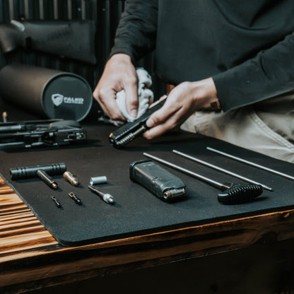 Person cleaning a firearm with tools on a table